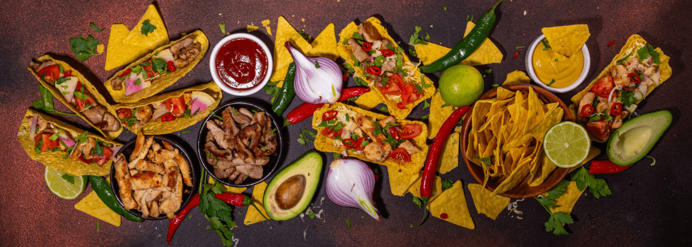 an assortment of vibrant Mexican cuisine spread with tacos, nachos, dips and fresh garnishes on rustic surface
