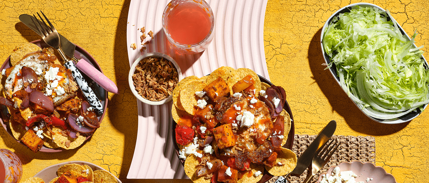 Plates of Vegetarian Pumpkin Capsicum Tomato Nachos on a yellow surface