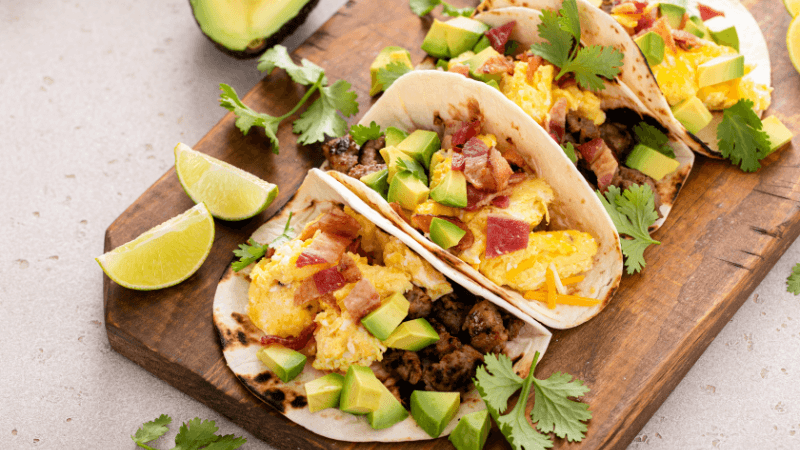 avocado eggs tacos garnished with coriander and lime served on wooden board