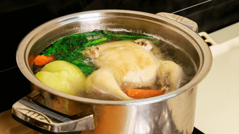 pot of chicken stock simmering on a gas stove