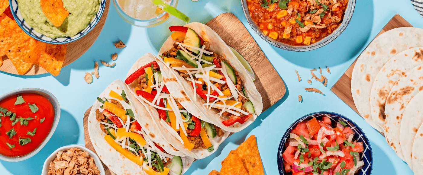 traditional mexican fajitas served on sky blue coloured table with side dishes such as guacamole, salsa, beans etc.