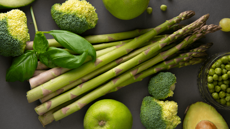 assorted green vegetables such as asparagus, broccoli, peas and kale put together on a table