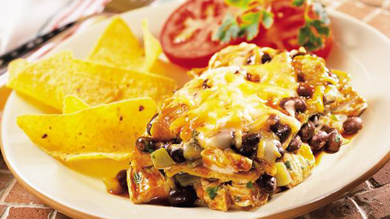 layered black bean enchiladas served on a plate with tortilla chips